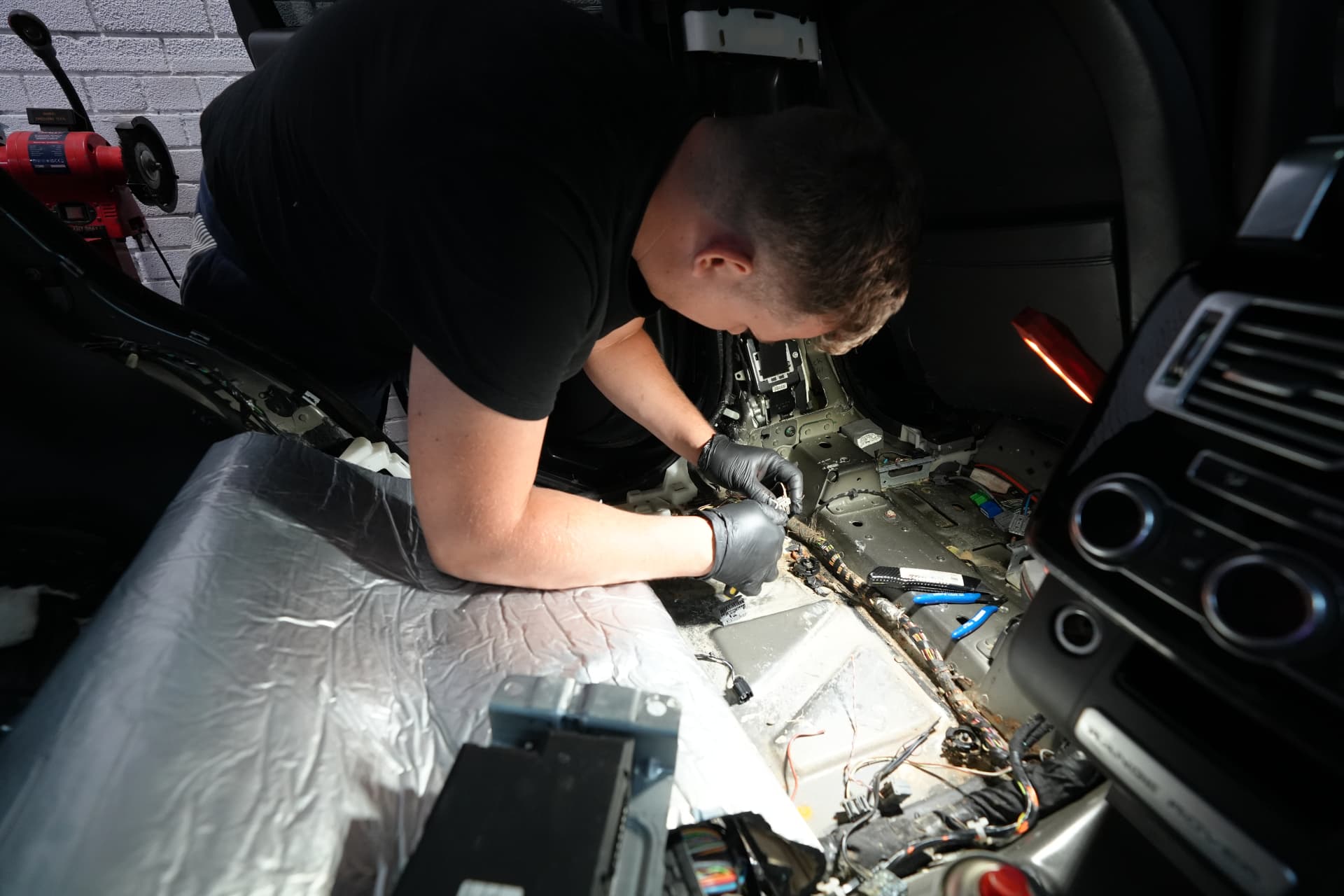 ProUK Garage mechanic working on vehicle wiring inside a car